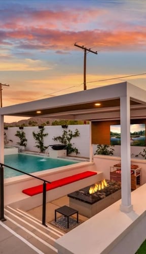 Backyard at sunset with pool, fire pit lounge, pergola, and putting green at Modern Desert Oasis