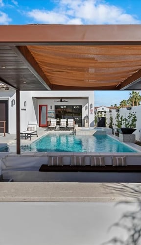 Covered patio with pool and outdoor TV at the Santa Barbara-Style Desert Retreat