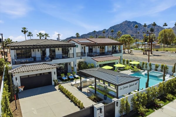 Modern two-story white villa with pool, pergola, and mountain views surrounded by palm trees