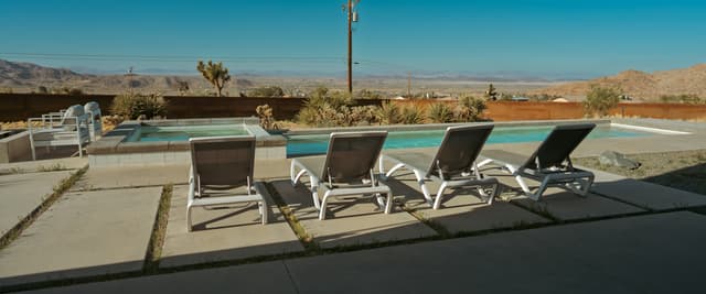 Desert pool with lounge chairs, open Coachella Valley views, and mountains under a deep blue sky